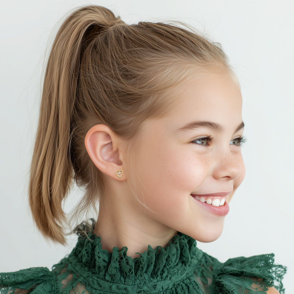 Child wearing Divine Love, Diamond Cut Heart with Clear CZ Stud Earrings in Yellow Gold with screwback post.