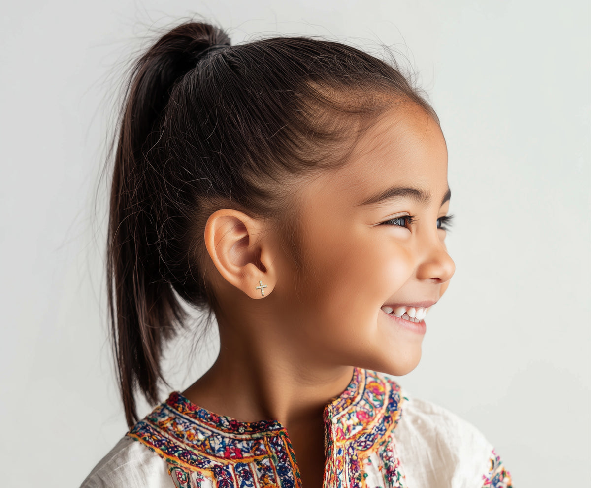 Child wearing Faithful Cross, Clear Pavé CZ Stud Earrings in Yellow Gold with screwback post.