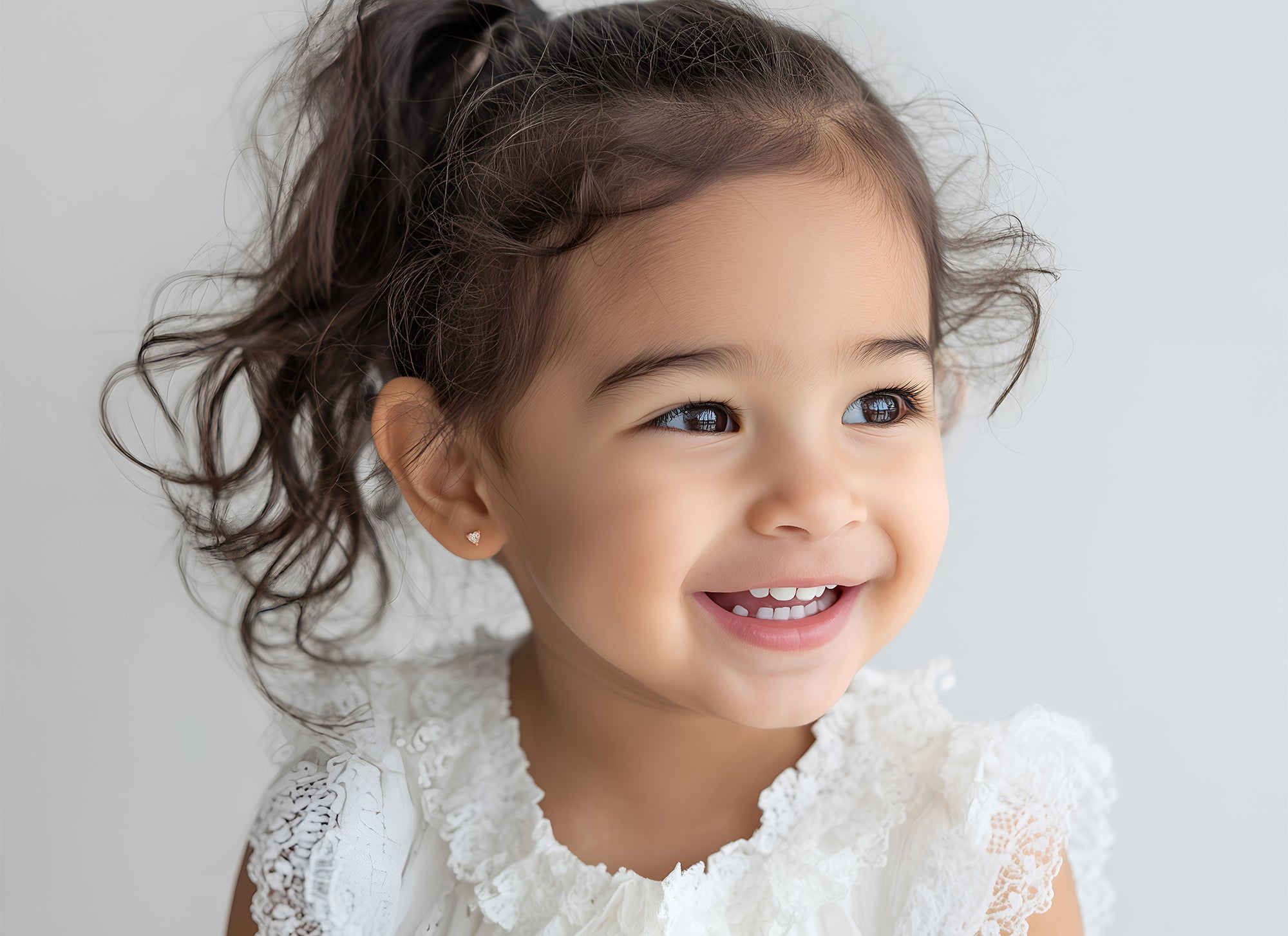 Toddler wearing rose gold clear CZ heart stud earrings with screwback post.