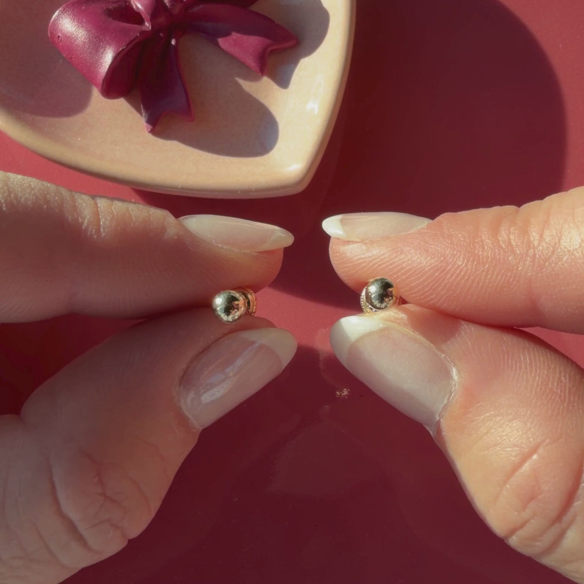 Video of 4mm classic round stud earrings in solid 14K yellow gold held in hand to show their actual size for babies and children.
