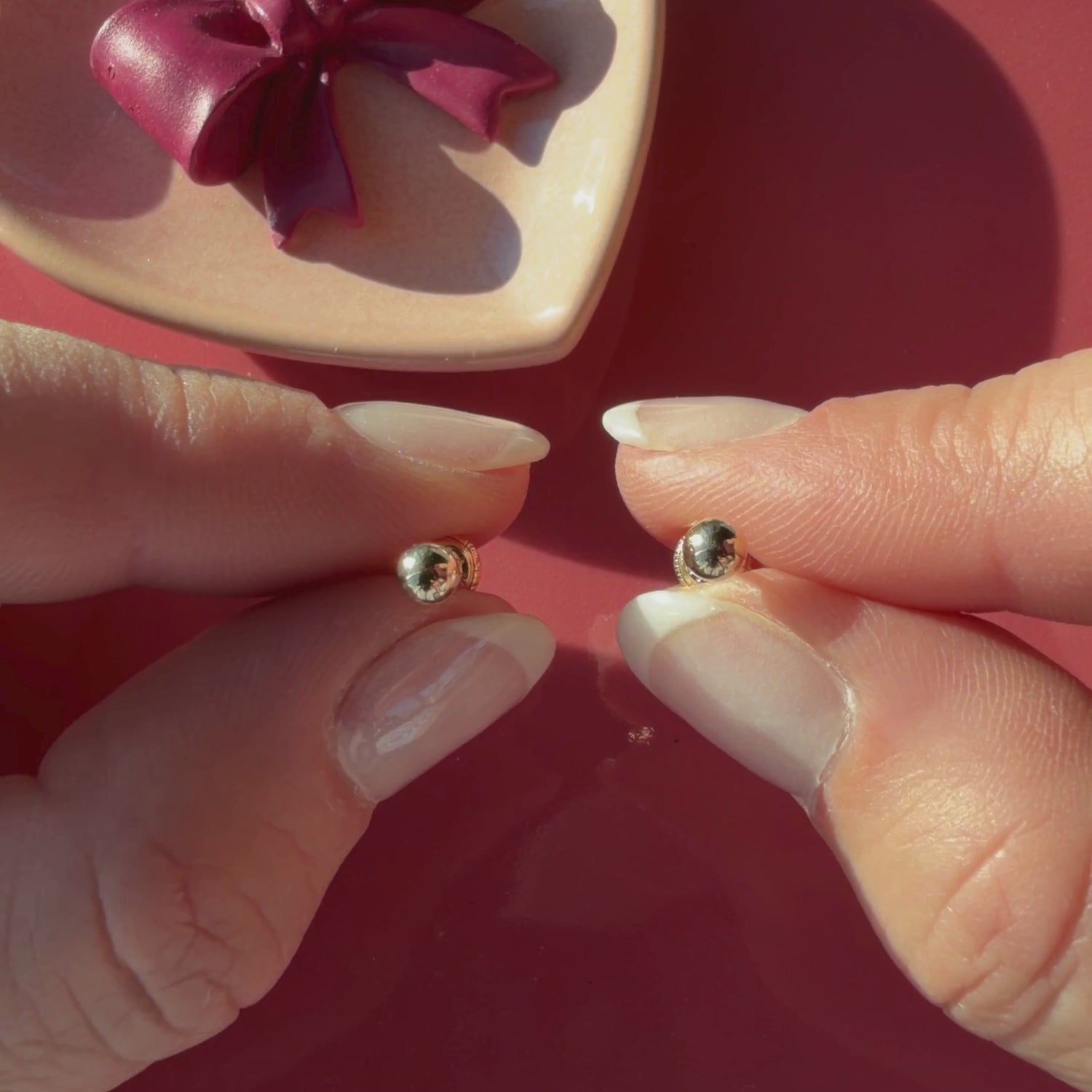 Video of 4mm classic round stud earrings in solid 14K yellow gold held in hand to show their actual size for babies and children.