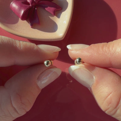 Video of 4mm classic round stud earrings in solid 14K yellow gold held in hand to show their actual size for babies and children.