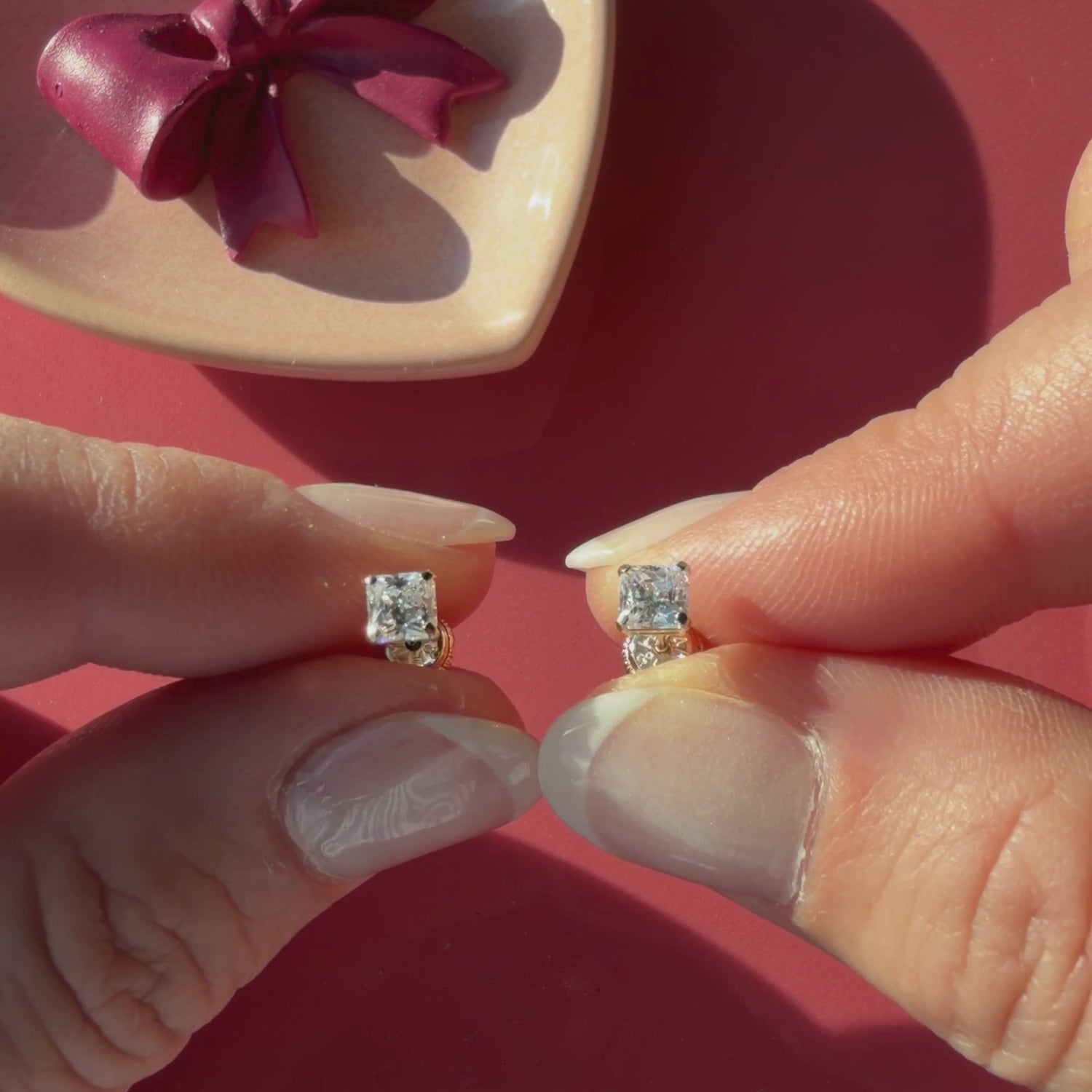 Video of 4mm clear princess cut CZ stud earrings in solid 14K yellow gold held in hand to show their actual size for babies and children.