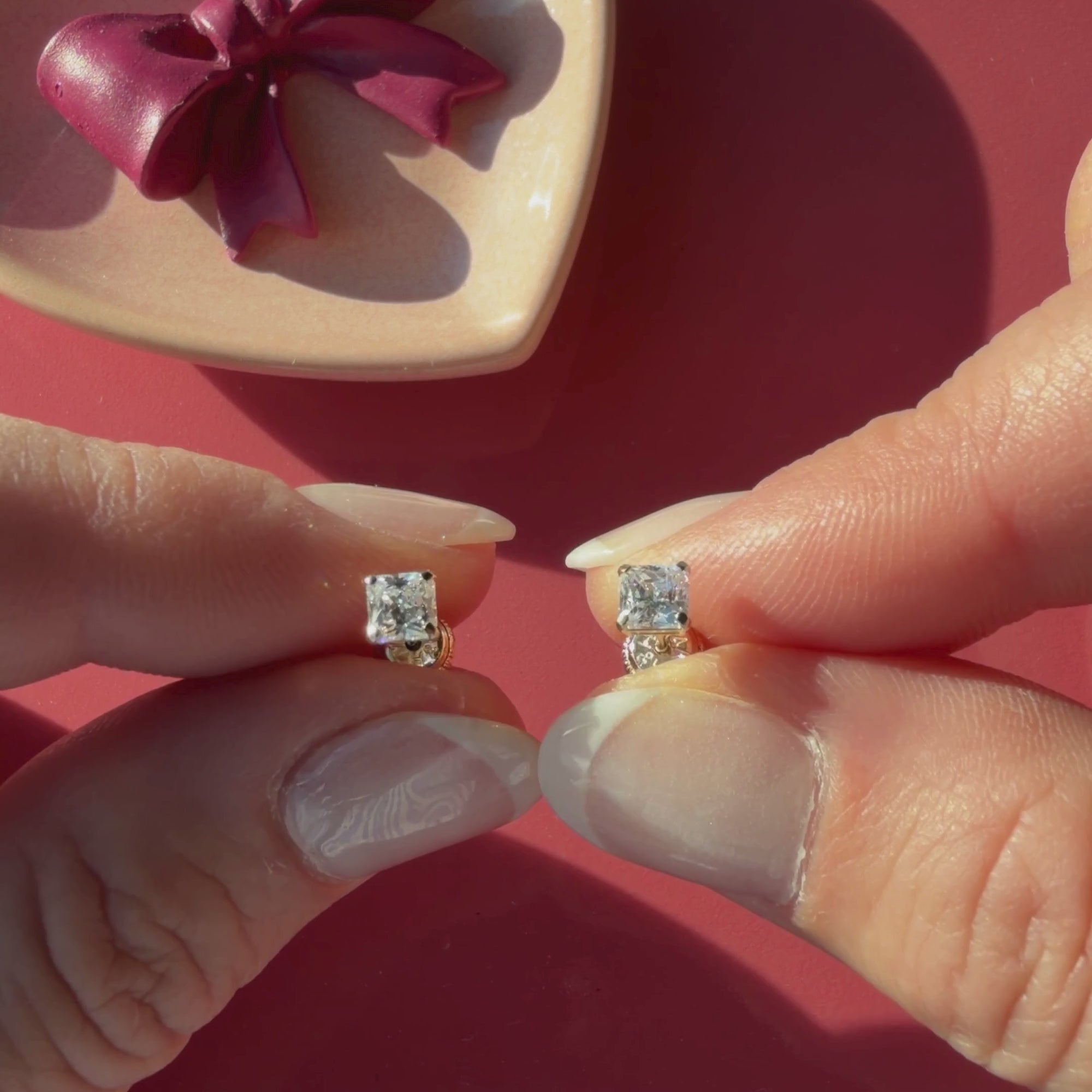 Video of 4mm clear princess cut CZ stud earrings in solid 14K yellow gold held in hand to show their actual size for babies and children.