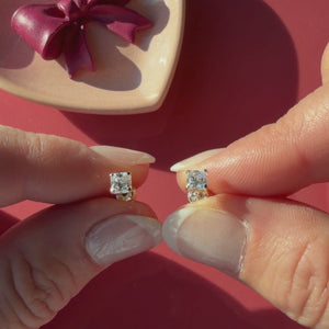 Video of 4mm clear princess cut CZ stud earrings in solid 14K yellow gold held in hand to show their actual size for babies and children.
