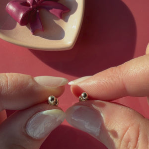 Video of 3mm classic round stud earrings in solid 14K yellow gold held in hand to show their actual size for babies and children.