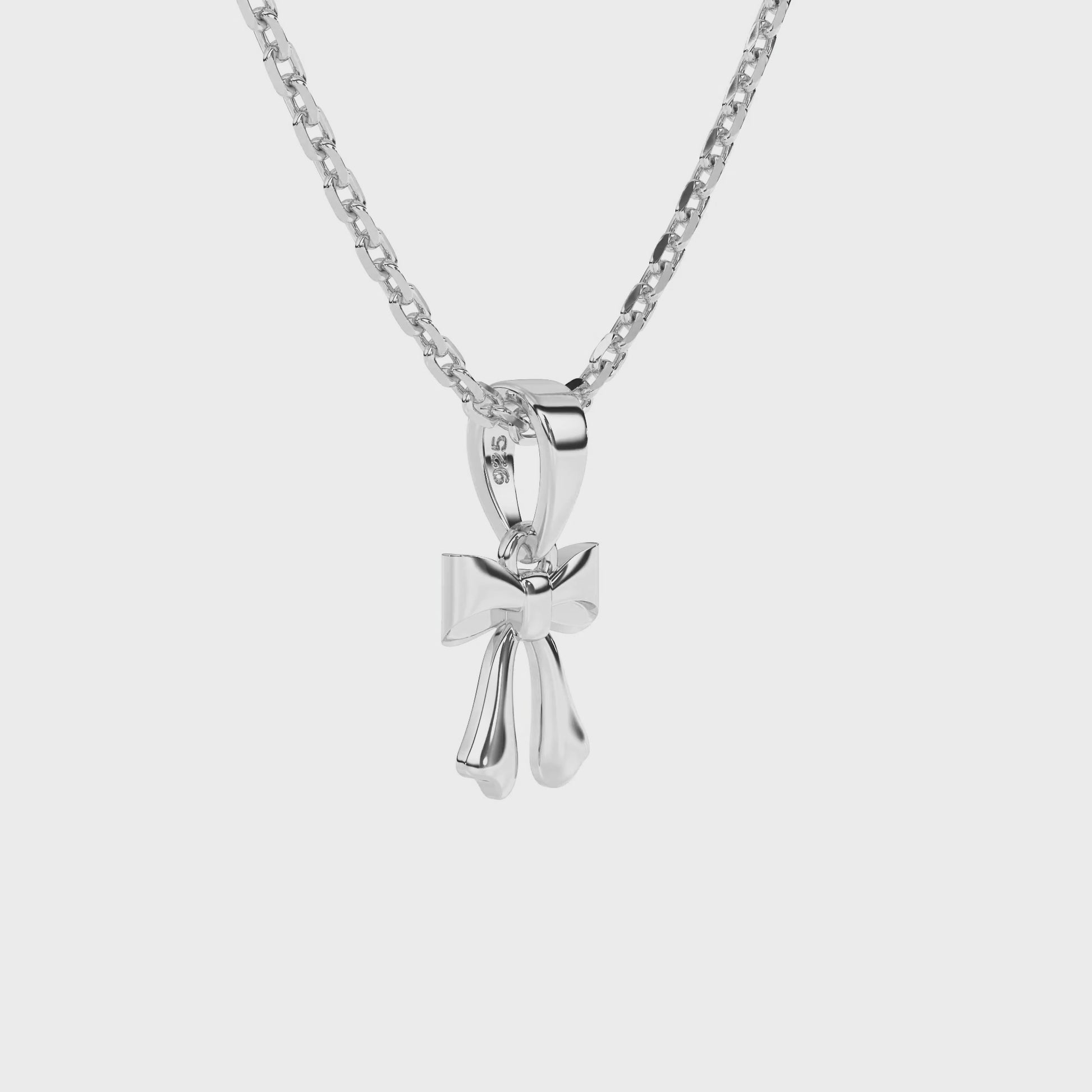 Sterling silver bow-shaped pendant on a necklace chain against a white background video.