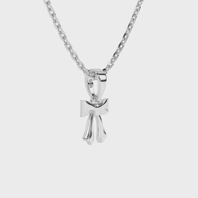 Sterling silver bow-shaped pendant on a necklace chain against a white background video.