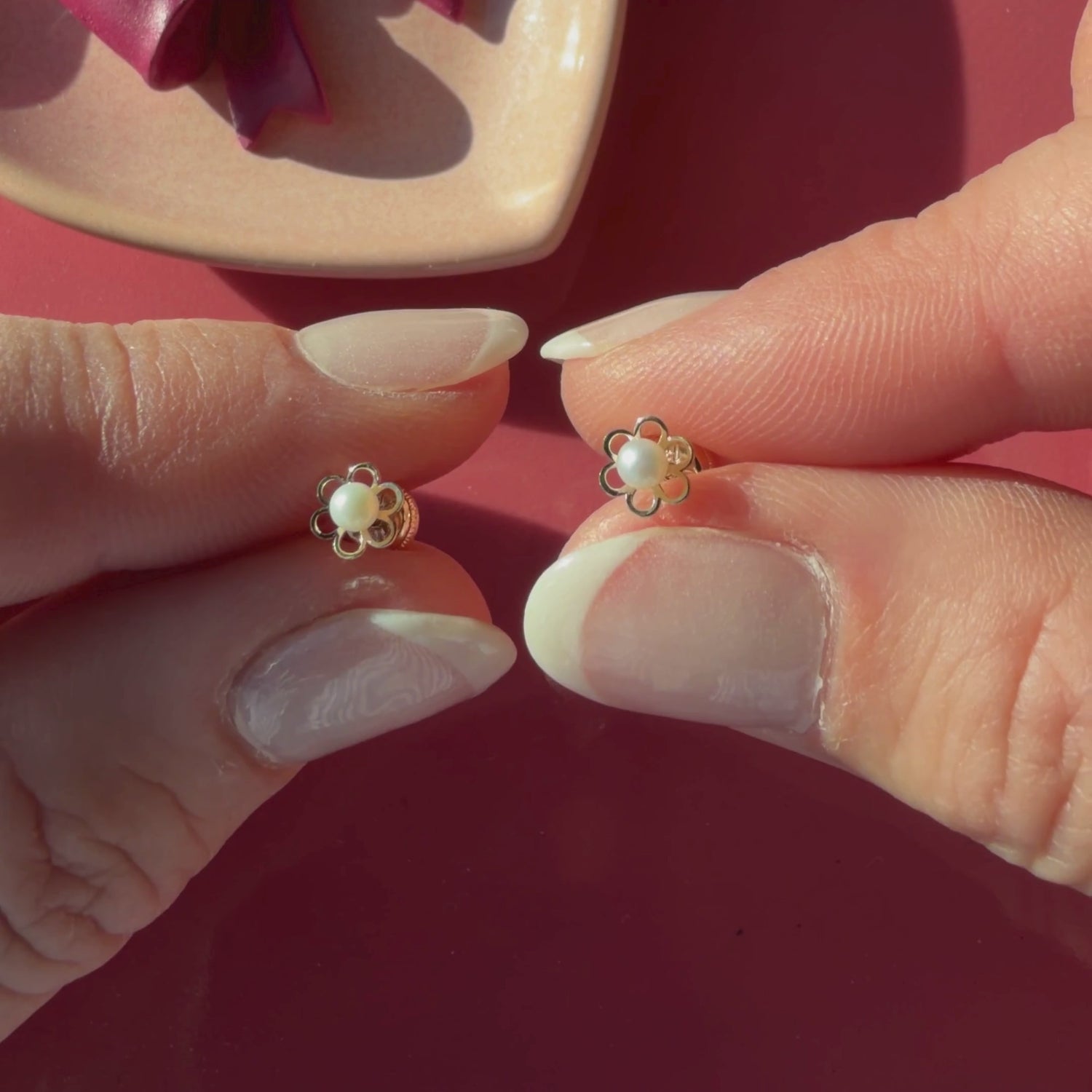 Video of Petals and Pearls AAA-pearl stud earrings in solid 14K yellow gold held in hand to show their actual size for babies and children.