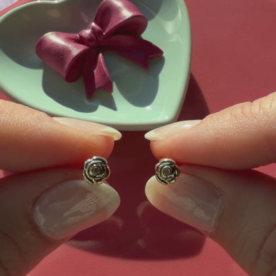 Video of Blooming Rose clear CZ stud earrings in solid 14K yellow gold held in hand to show their actual size for babies and children.