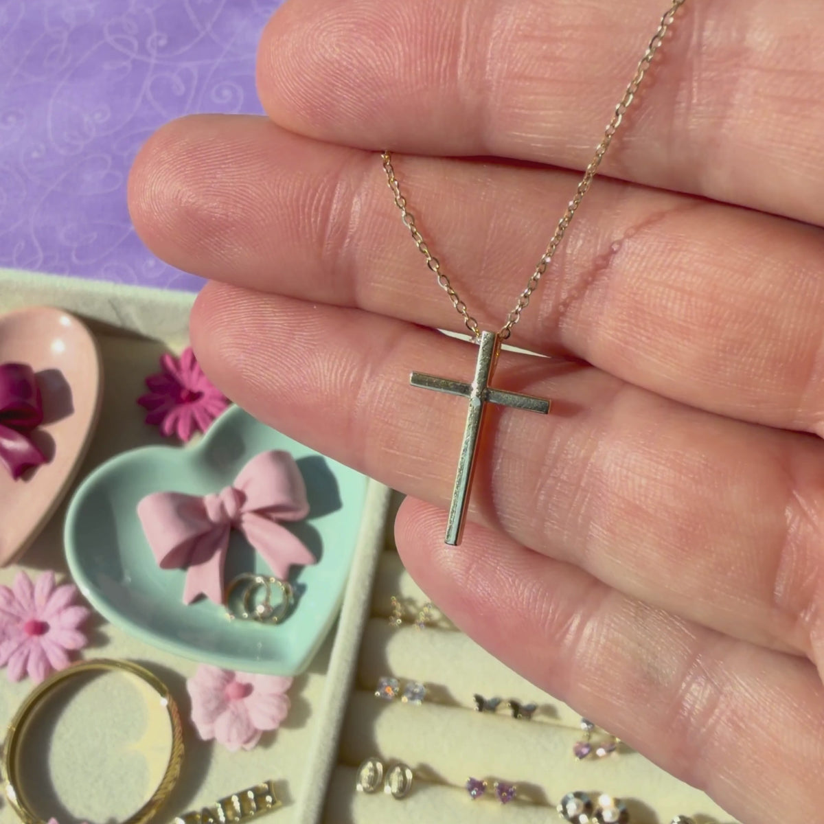 Modern Faith 14k Yellow Gold cross necklace pendant held in hand to show its actual size.