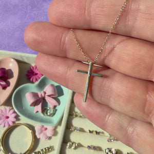 Modern Faith 14k Yellow Gold cross necklace pendant held in hand to show its actual size.