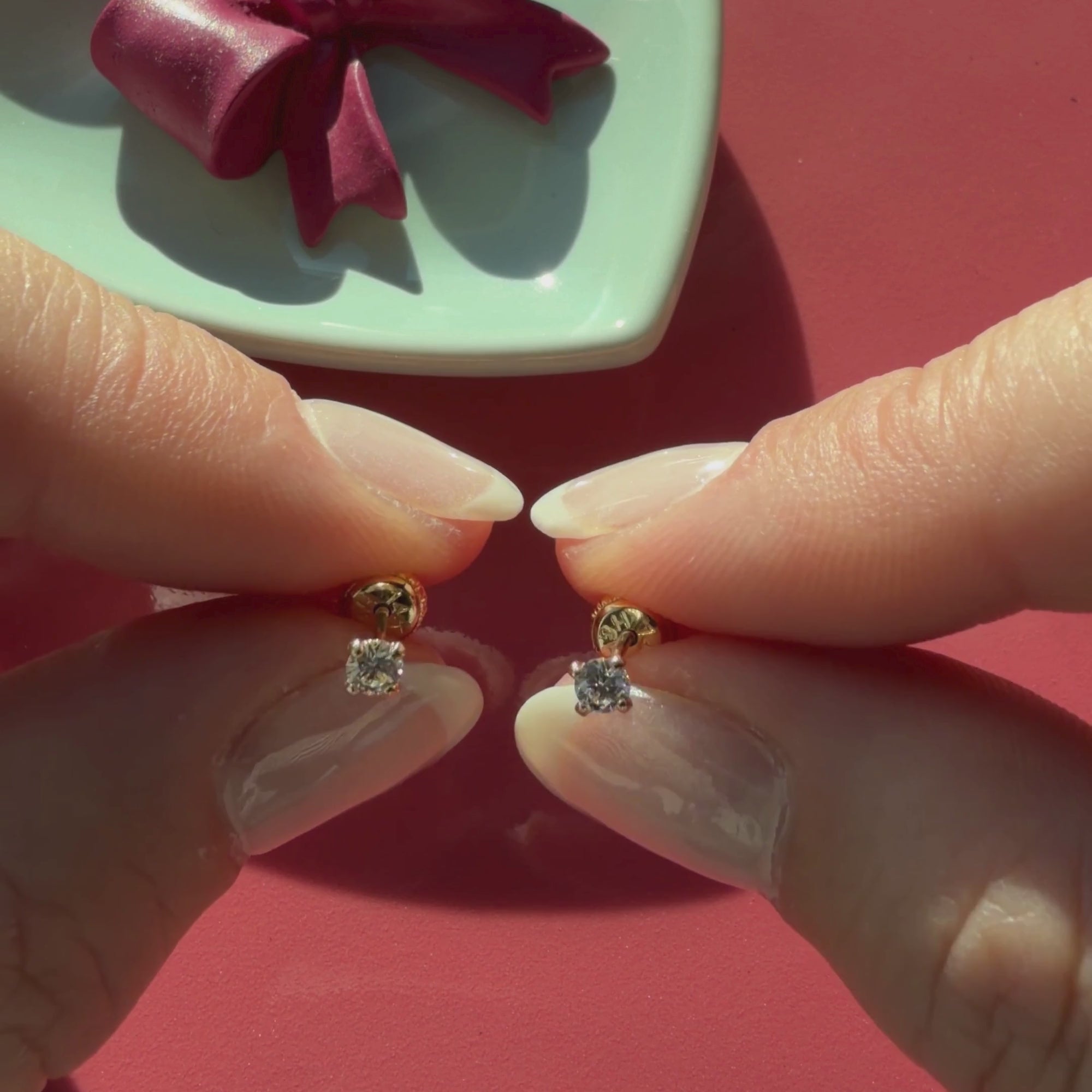 Video of 3mm clear round CZ stud earrings in solid 14K yellow gold held in hand to show their actual size for babies and children.