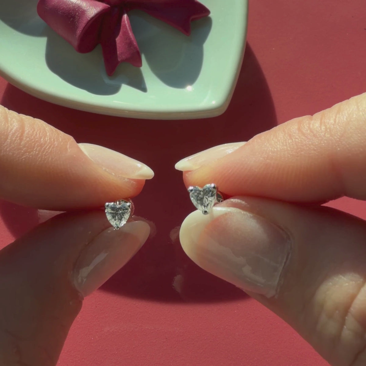 Video of 4mm clear heart CZ stud earrings in solid 14K white gold held in hand to show their actual size for babies and children.