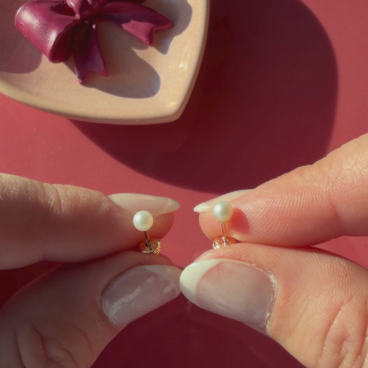 Video of 3mm pearl stud earrings in solid 14K yellow gold held in hand to show their actual size for babies and children.