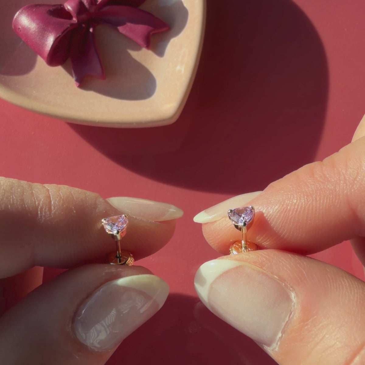 Video of 4mm pink heart CZ stud earrings in solid 14K yellow gold held in hand to show their actual size for babies and children.
