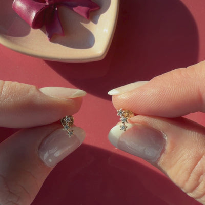 Video of Lucky Stars clear CZ stud earrings in solid 14K yellow gold held in hand to show their actual size for babies and children.