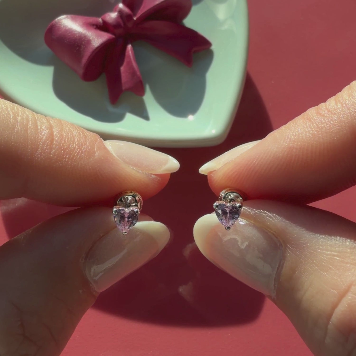 Video of 4mm pink heart CZ stud earrings in solid 14K white gold held in hand to show their actual size for babies and children.