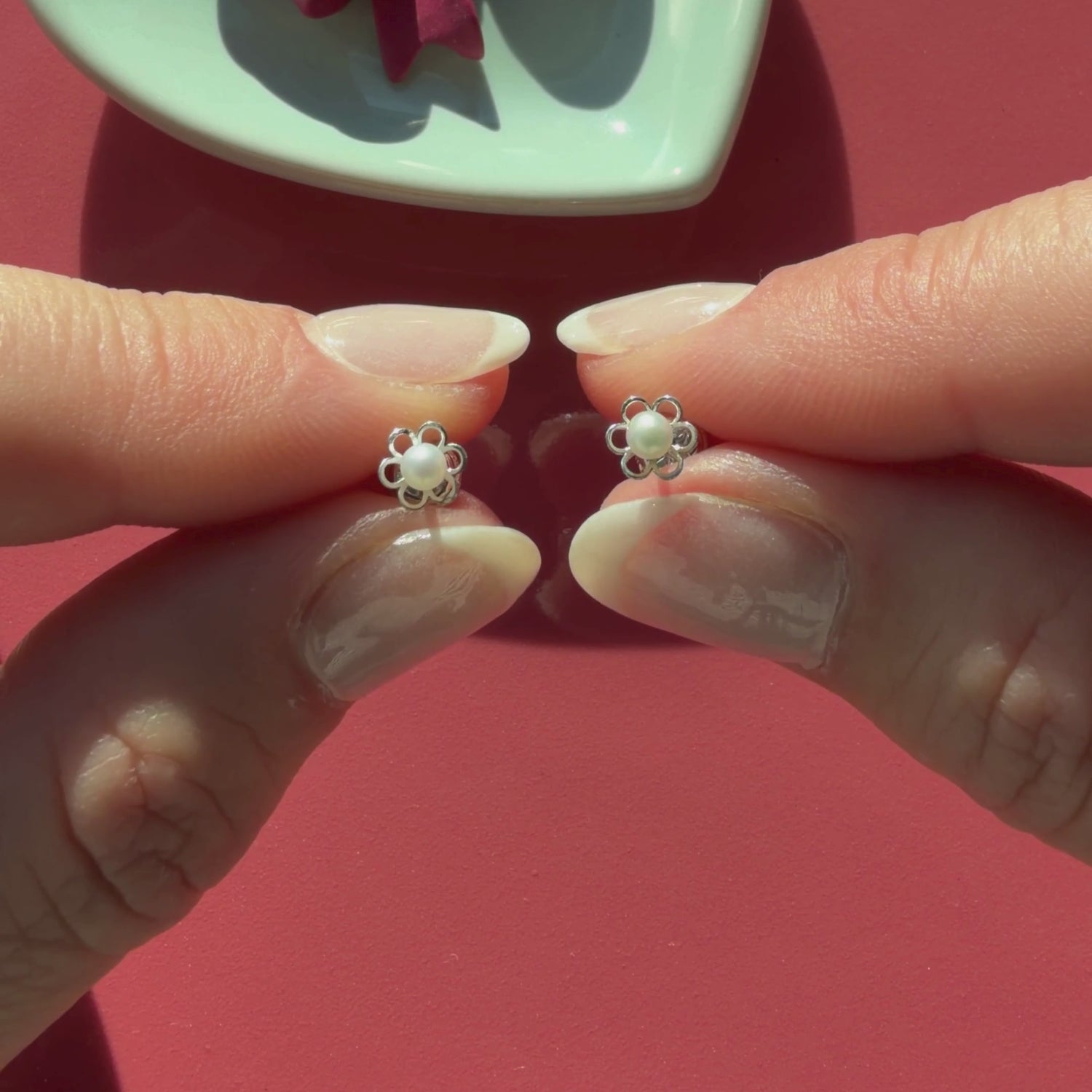 Video of Petals and Pearls AAA-pearl stud earrings in solid 14K white gold held in hand to show their actual size for babies and children.