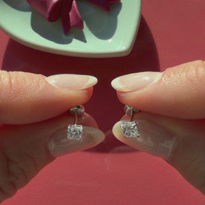 Video of 4mm clear princess cut CZ stud earrings in solid 14K white gold held in hand to show their actual size for babies and children.