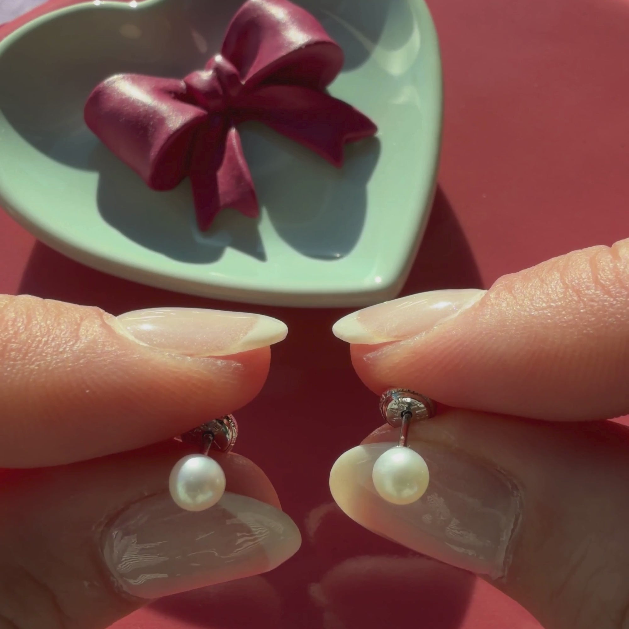 Video of 4mm pearl stud earrings in solid 14K white gold held in hand to show their actual size for babies and children.