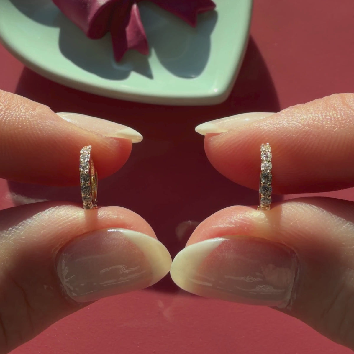 Video of 9mm halo pave clear CZ huggie hoop earrings in solid 14K yellow gold held in hand to show their actual size for babies and children.
