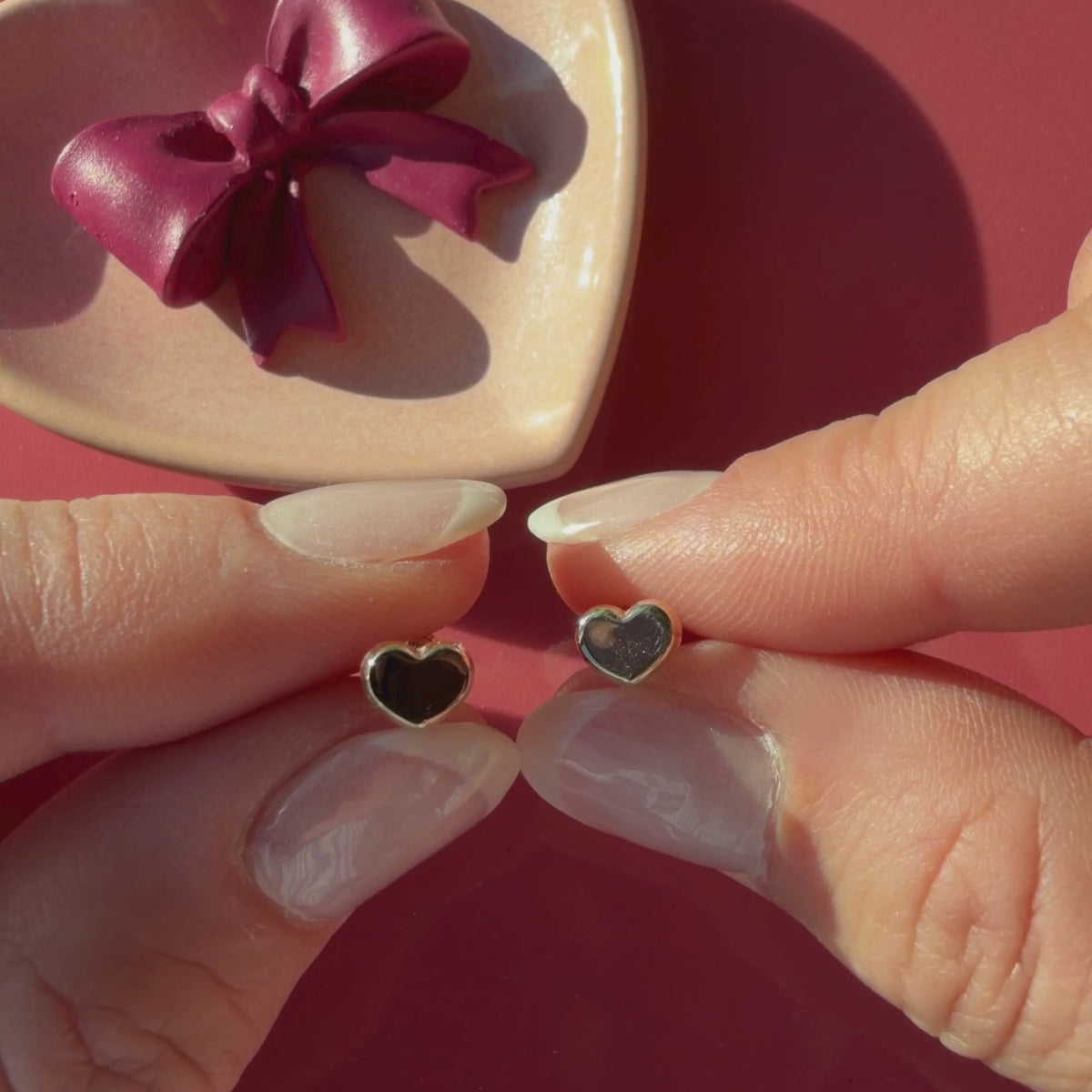 Video of Elegant Heart stud earrings in solid 14K yellow gold held in hand to show their actual size for babies and children.