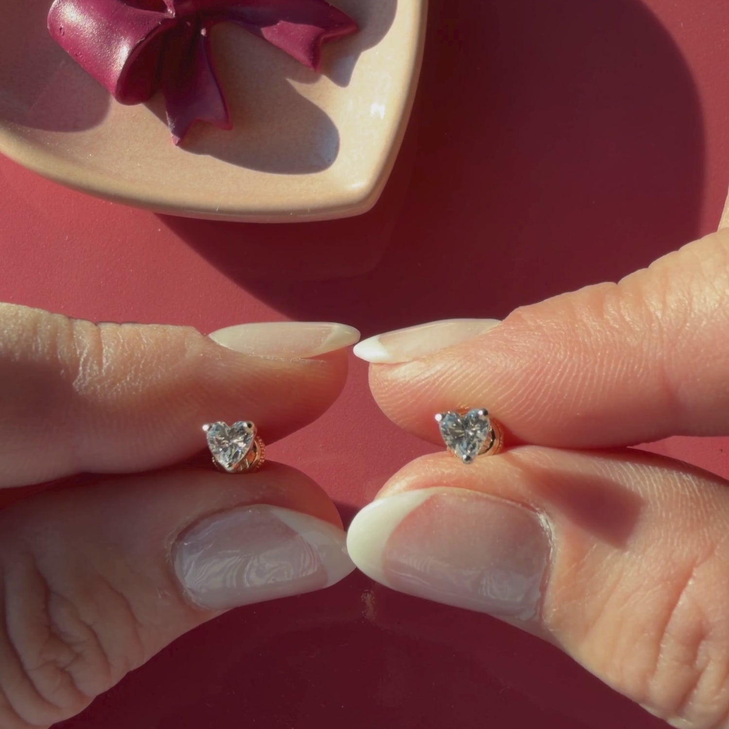 Video of 4mm clear heart CZ stud earrings in solid 14K yellow gold held in hand to show their actual size for babies and children.