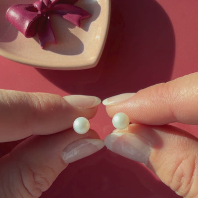 Video of 5mm pearl stud earrings in solid 14K yellow gold held in hand to show their actual size for babies and children.